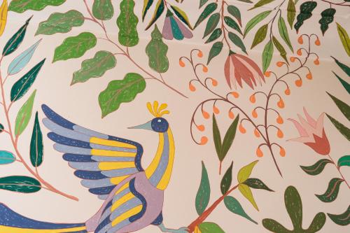 a colorful bird on a wall with leaves at Riad Pompon in Marrakech
