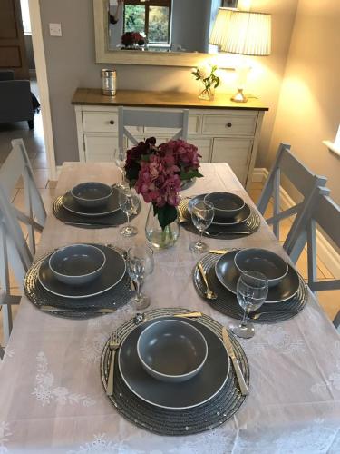 a table with plates and glasses and flowers on it at Holiday Home Dingle in Dingle