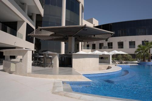 a large building with a swimming pool and a patio with a umbrella at Ray Hotel in Kuwait