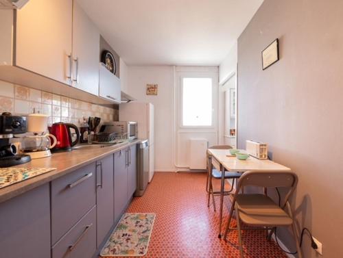 une cuisine avec une table et une petite table avec des chaises dans l'établissement Lhuisne, au Mans