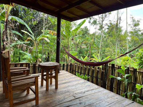 a hammock on a deck with a chair and a table at Mimi homestay-LOMBOK in Tetebatu