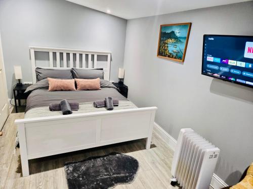 a bedroom with a white bed and a flat screen tv at Achnamara-Self Check In in Portree