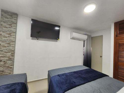 a bedroom with two beds and a tv on the wall at Apartment Pimienta in Chetumal