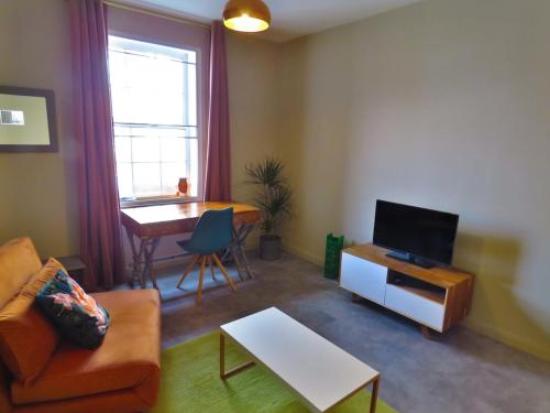 a living room with a couch and a tv and a table at Central London Spitalfields Apartment in London