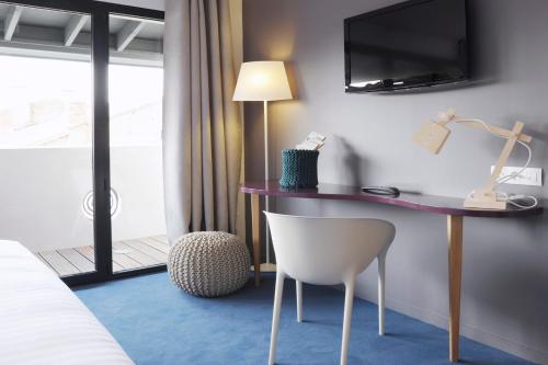 a hotel room with a desk and a chair at L’Échappée Belle in LʼIsle-Jourdain