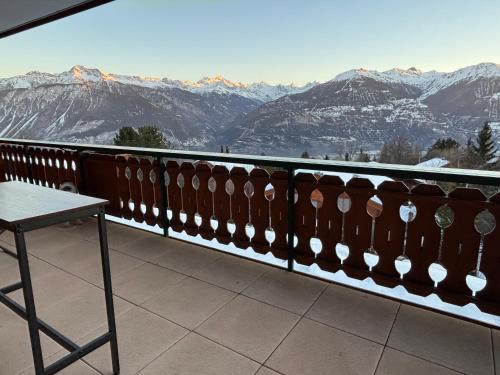 a balcony with a table and a view of mountains at A mountain home away from home in Crans-Montana