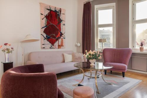 Una sala de estar con un sofá y dos sillas y una mesa. en Lovely Vintage Suite, autohalli, en Helsinki