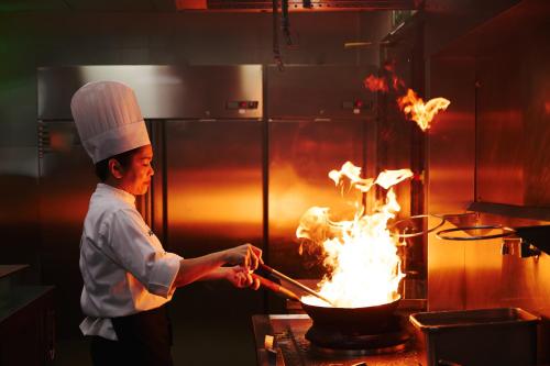 a chef cooking food in a pot on a stove at Dusit Doha Hotel in Doha