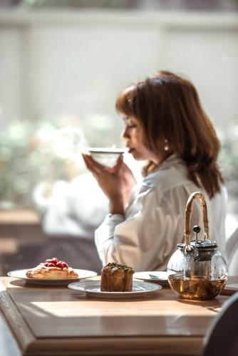 a woman sitting at a table drinking from a cell phone at Dusit Doha Hotel in Doha
