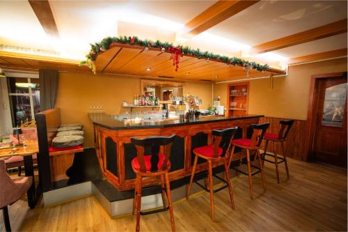 a bar in a restaurant with red chairs at Berghotel Drei Brüder Höhe in Marienberg