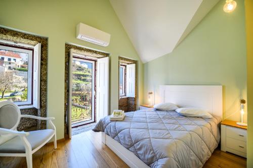 a bedroom with a large bed and two windows at Casa da Fândega in Loriga