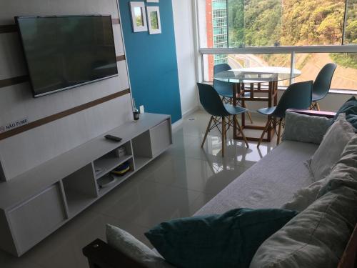 a living room with a couch and a tv and a table at Apartamento Studio Superior com vista da BIG Wheel in Balneário Camboriú