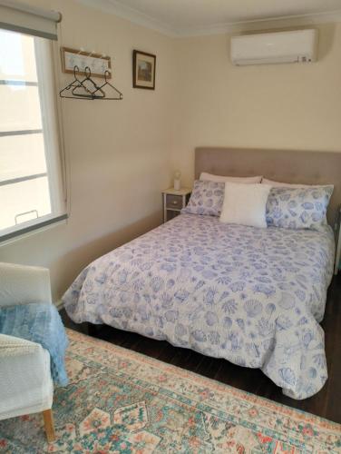 a bedroom with a bed with a blue comforter and a window at Avonlea Cottages in York
