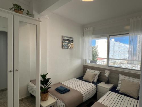a small bedroom with two beds and a window at SOLMAR Playa Gandia SOLO FAMILIAS in Playa de Gandia