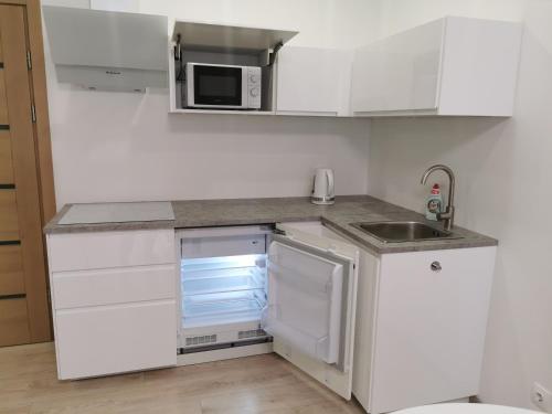 a white kitchen with a sink and a refrigerator at Ragaines apartamentai self check-in in Klaipėda