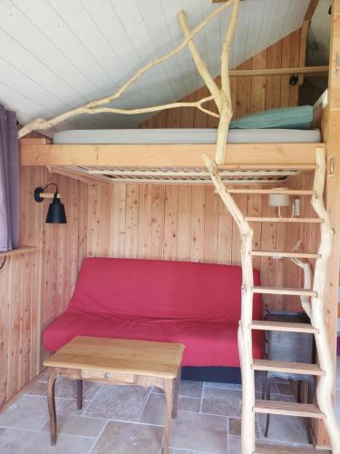 une chambre avec un canapé rouge dans une cabane dans les arbres dans l'établissement Le Chat qui pêche, maisonnette en bois, Les Kabanes en Kreiz Breizh, à Rostrenen