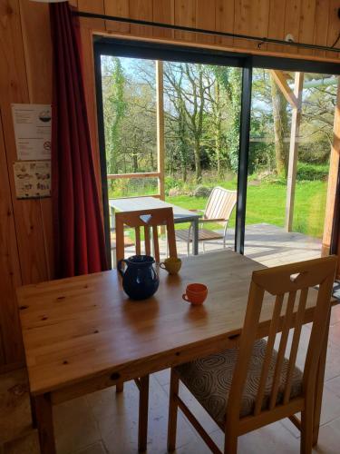 - une table en bois avec 2 chaises et un bol sur le dessus dans l'établissement Le Chat qui pêche, maisonnette en bois, Les Kabanes en Kreiz Breizh, à Rostrenen