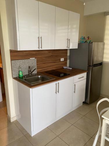 a kitchen with white cabinets and a sink and a refrigerator at Apartamento karma in Culebra