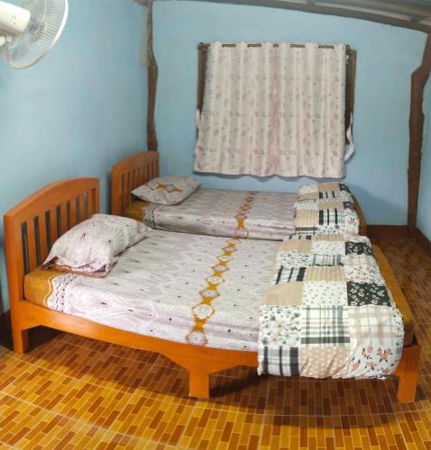 two twin beds in a room with a window at Billy the Homestay in Chiang Dao
