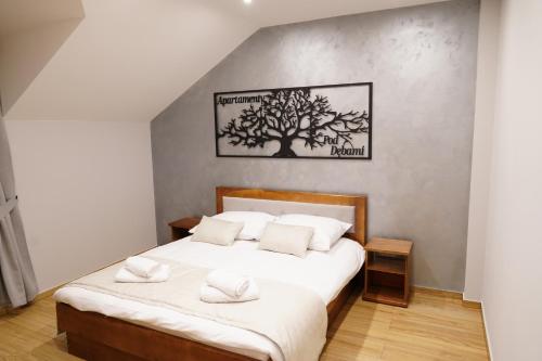 a bedroom with a bed with a tree picture on the wall at Apartamenty pod Dębami - noclegi Beskid Niski in Odrzechowa