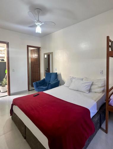 a bedroom with a large bed and a blue chair at Âncora Lofts in Arraial do Cabo