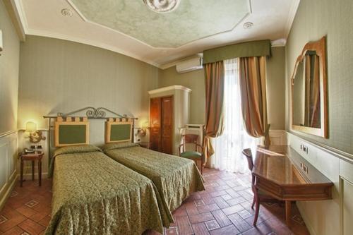 a bedroom with a bed and a desk and a window at Hotel Pedrini in Bologna