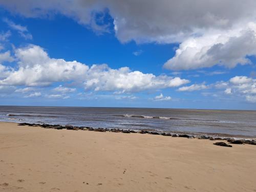 a beach with the ocean and a cloudy sky at California beachhut chalet in Great Yarmouth