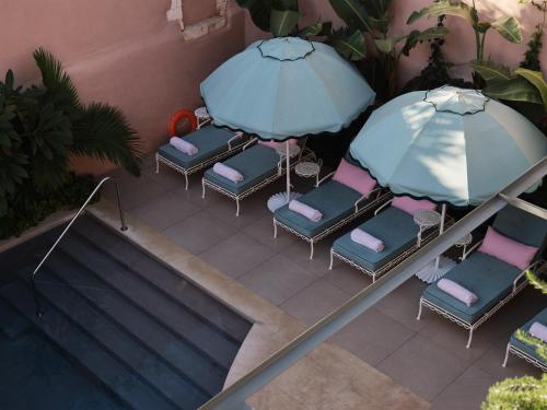 a group of chairs with umbrellas next to a swimming pool at Domus Blanc Boutique Hotel in Chania Town