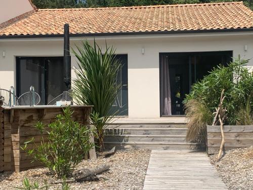 une maison avec des portes noires et une passerelle en bois dans l'établissement Du sable et des pins, au Le Verdon-sur-Mer