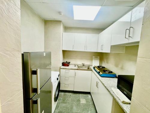 Una cocina con gabinetes blancos y un refrigerador de acero inoxidable. en Haifa building, en Dubái