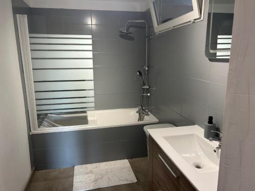 a bathroom with a bath tub and a sink at La Ferme in Roye