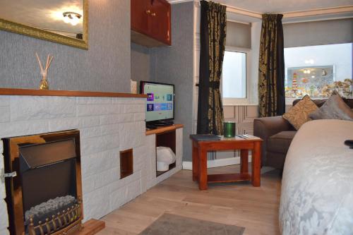 a bedroom with a living room with a fireplace at Kilbrannan Guest House in Great Yarmouth