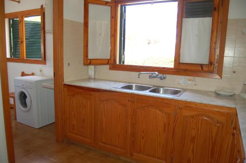 a kitchen with a sink and a washing machine at Illa Colom in Cala en Bosc
