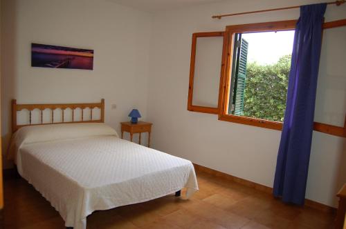 a bedroom with a bed and a window at Illa Colom in Cala en Bosc