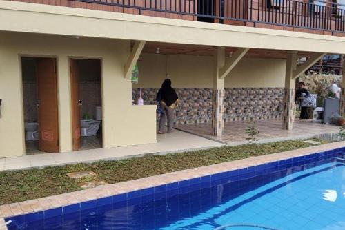 a woman standing next to a house with a swimming pool at Villa Zoya 1 in Bogor