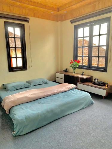 a large bedroom with two beds and two windows at Rosa Homestay in Ấp Trạm Hành