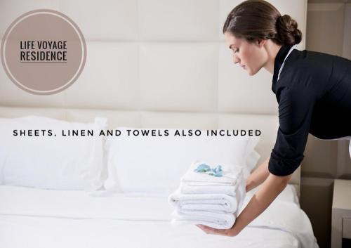 a woman is putting towels on a bed at LIFE VOYAGE & SPA - Strasbourg's City Center Luxury Experience in Strasbourg