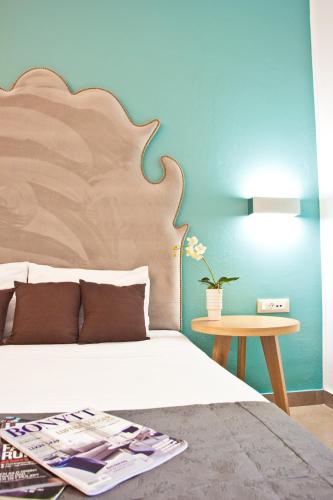 a bedroom with a bed with a wooden headboard and a table at Malibu Boutique Studios & Bungalows in Faliraki