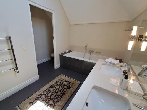 a white bathroom with a tub and a sink and a bath tub at Wild Mushroom Country House in Stellenbosch