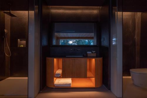 a bathroom with a tv and a sink and a tub at Anlai Rainforest Wild Luxury Hotel in Jinghong
