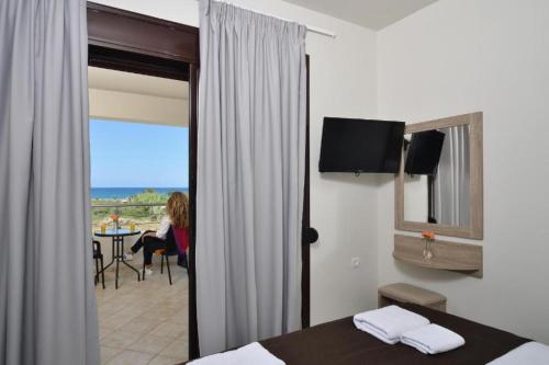 a woman sitting at a table in a hotel room at Carisa Suites and Apartments in Maleme