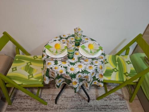 a table with two chairs and a table cloth with flowers at Nela Apartmani in Niš