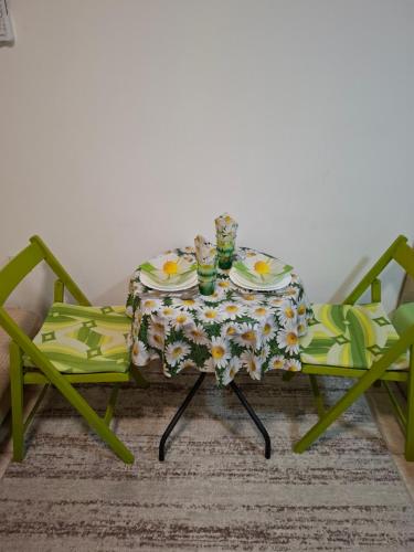 a table with two chairs and a table with a tableclotholitics at Nela Apartmani in Niš