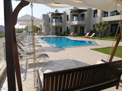 a view of a swimming pool with chairs and an umbrella at Carisa Suites and Apartments in Maleme