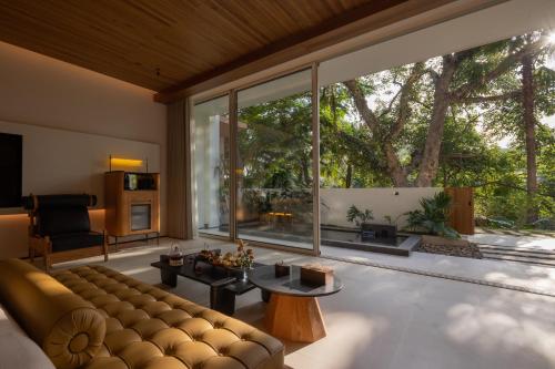 a living room with a couch and a large window at Anlai Rainforest Wild Luxury Hotel in Jinghong