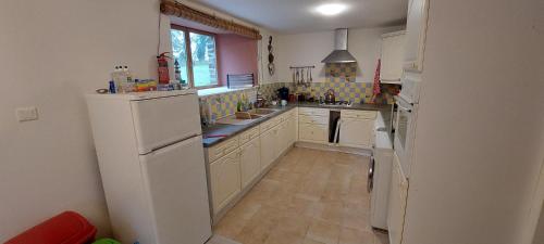  La cuisine est équipée de placards blancs et d'un réfrigérateur. dans l'établissement Green Acres Bretagne, à Maël-Carhaix