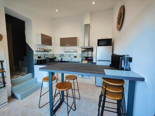 una cucina con piano di lavoro blu e sgabelli di Maison classé 3 étoiles Pérols avec terrasse et clim a Pérols