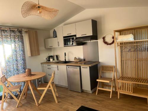 une petite cuisine avec une table et une table et des chaises dans l'établissement Studio en dépendance aux portes de l ocean, à Saint-Médard-en-Jalles