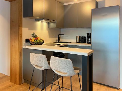 a kitchen with two chairs and a counter with a sink at Apartments Max & Moritz in Kirchberg in Tirol