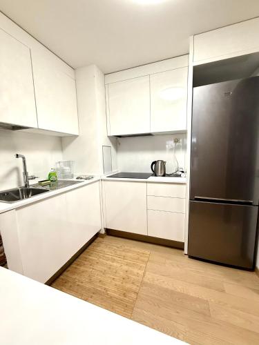a kitchen with white cabinets and a stainless steel refrigerator at Monaco, elegant & quiet renovated apartment, with terrace & pool, 15min walk to Port Hercule in Monte Carlo